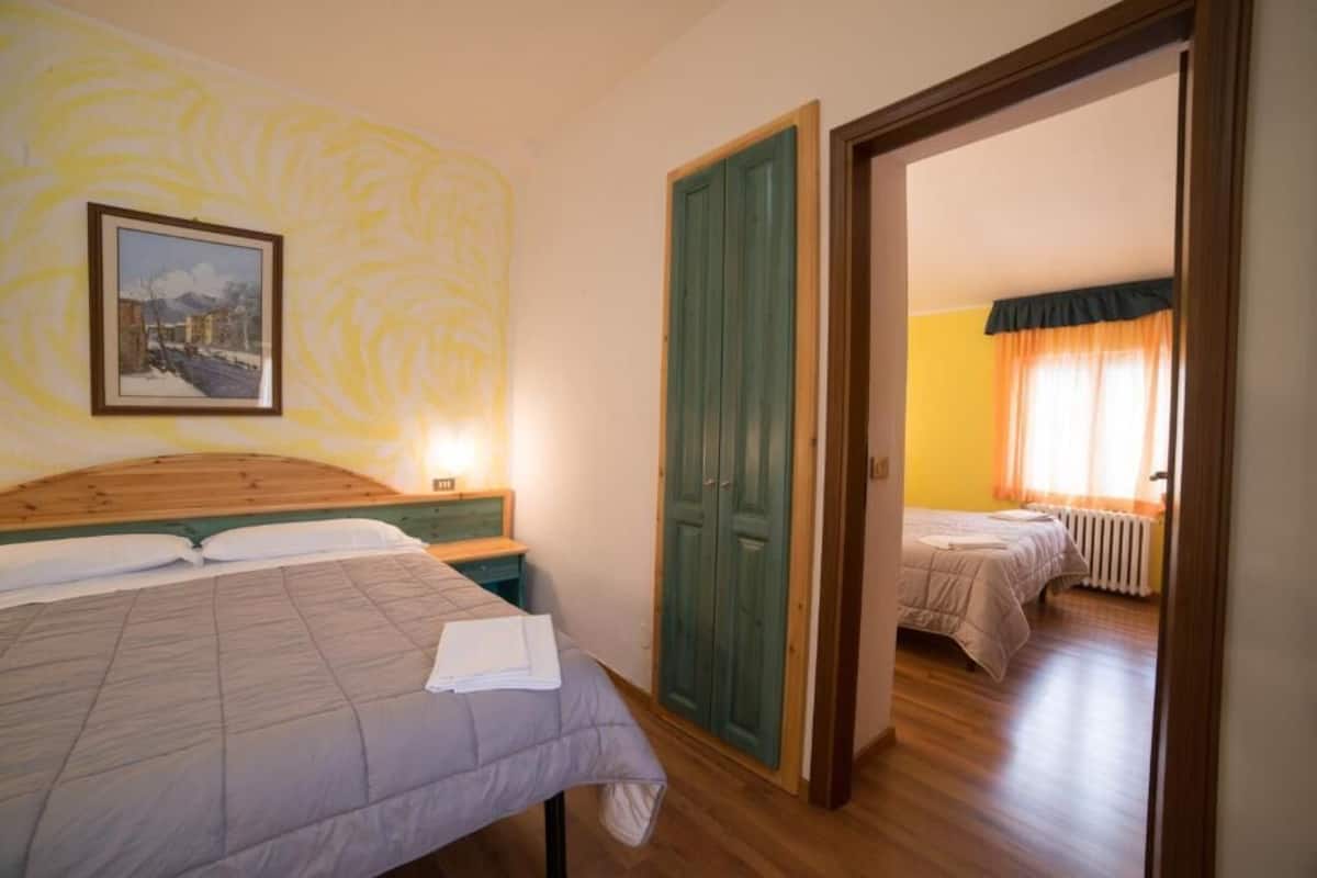 A bedroom with two beds, a wooden headboard, a framed picture on the wall, and a green door.