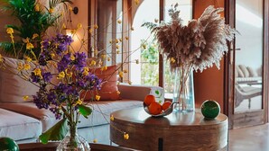 Ein Wohnzimmer mit einem runden Holztisch, einer Couch und einer Blumenvase.