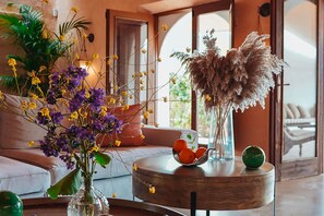 Ein Wohnzimmer mit einem runden Holztisch, einer Couch und einer Blumenvase.