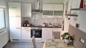 A modern kitchen with white cabinets, a dining table with a floral tablecloth, and a potted plant. - Vacation apartment in Bönnigheim, detached house near Tripsdrill adventure park (Bönnigheim)