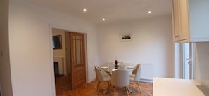 A dining area with a table set for four, a white cabinet, and a radiator.
