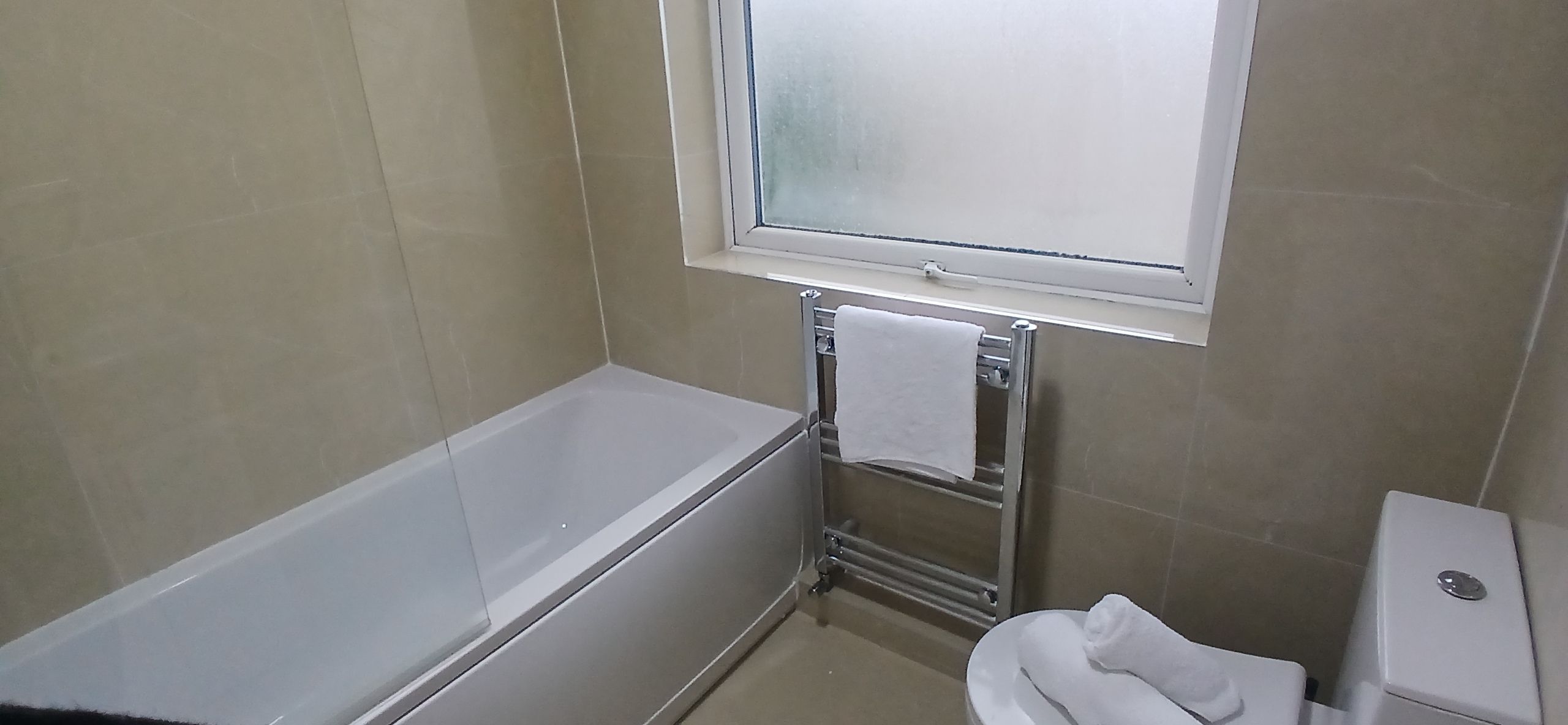 A bathroom with a bathtub, a toilet, and a window.