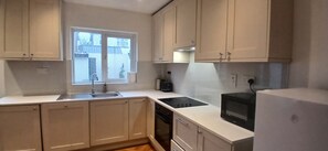 A kitchen with a window, a sink, a stove, and a refrigerator.