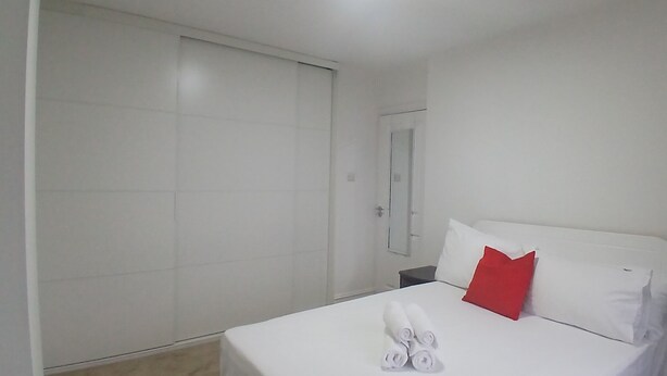 Ein Hotelzimmer mit einem Bett, einem roten Kopfkissen, einem weißen Kopfkissen und einem weißen Handtuch.