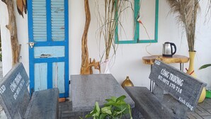 A rustic outdoor seating area with stone benches, a blue door, and decorative plants. - Beautiful 3-bedroom villa with AC in charming Phú Quốc (PHÚ QUỐC)