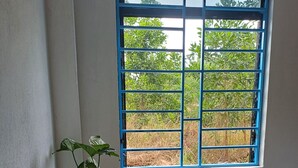 A room with a bed, a window with blue bars, a wooden table with a plant, water bottles, and a small figurine. - Beautiful 3-bedroom villa with AC in charming Phú Quốc (PHÚ QUỐC)