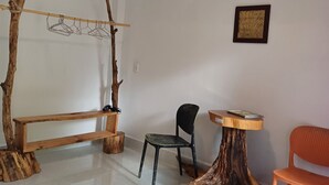 A room with a wooden bench, a chair, a small table, and a wall-mounted air conditioner. - Beautiful 3-bedroom villa with AC in charming Phú Quốc (PHÚ QUỐC)