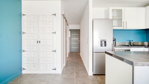 Una cuina moderna amb armaris blancs, un refrigerador d'acer inoxidable i una paret d'accent blava.
