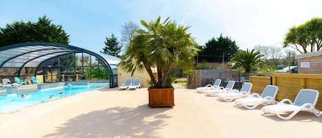 A pool area with lounge chairs and a covered swimming area.