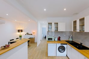 A modern kitchen with a microwave, toaster, and washing machine. - Embrun apartment – in the heart of Portbail – with access to the swimming pool (Port-Bail-sur-Mer)