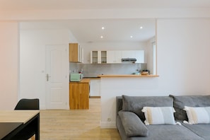 A modern apartment with a kitchen, dining area, and living room. - Embrun apartment – in the heart of Portbail – with access to the swimming pool (Port-Bail-sur-Mer)