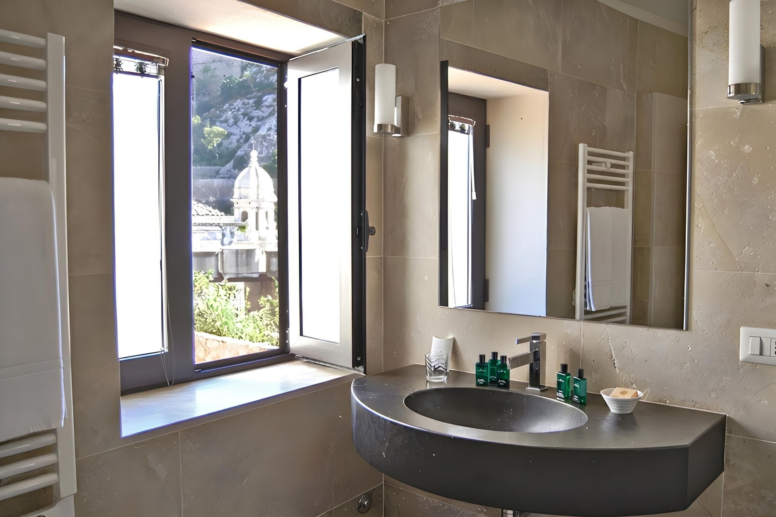 A bathroom with a large window, a sink, and a mirror.