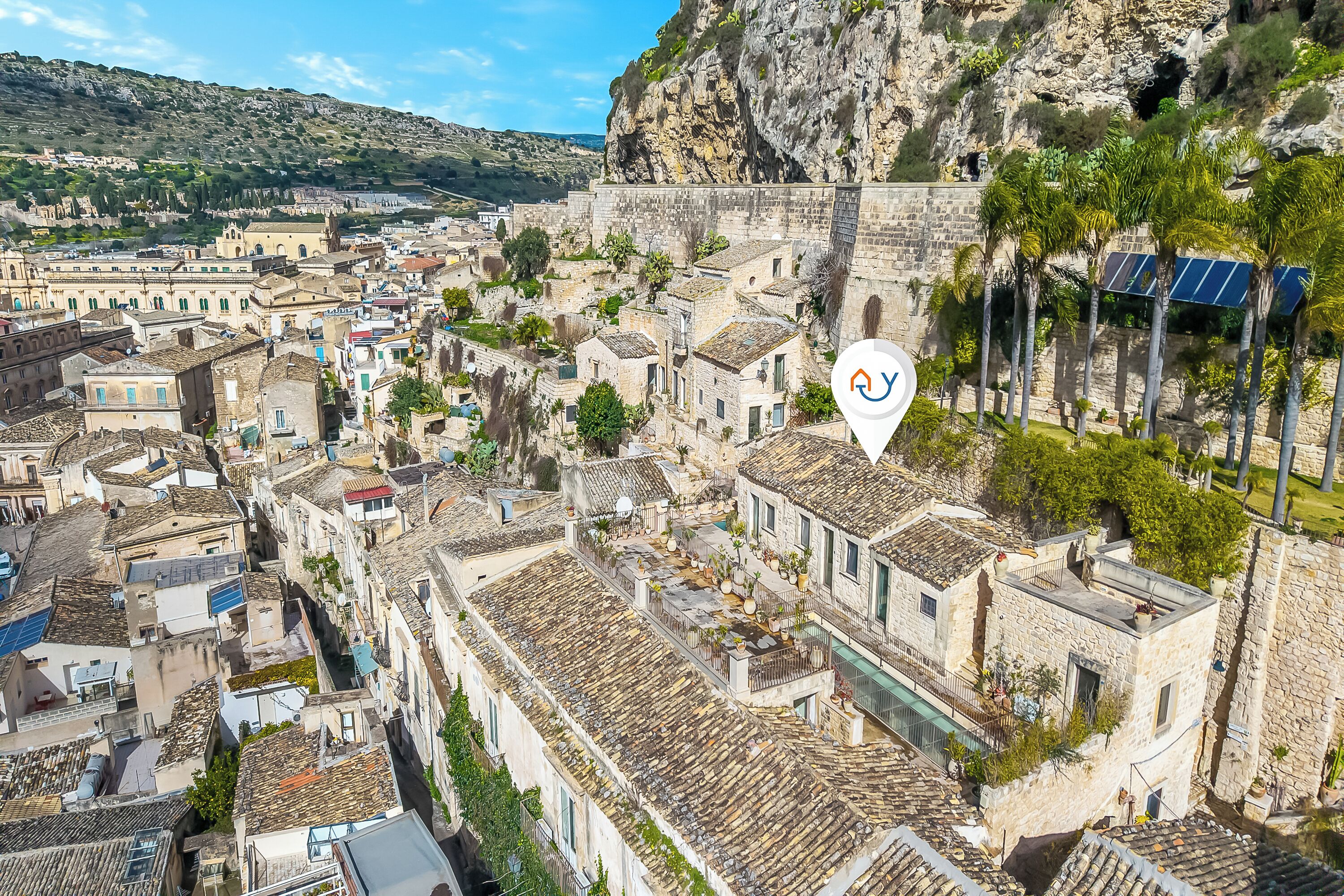 A historic town with stone buildings, narrow streets, and a prominent cliff.