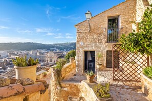 A stone building with a balcony overlooking a cityscape. - Borgo Hedonè (Scicli)