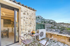 A stone building with a balcony, a table with chairs, and a view of a rocky landscape. - Borgo Hedonè (Scicli)