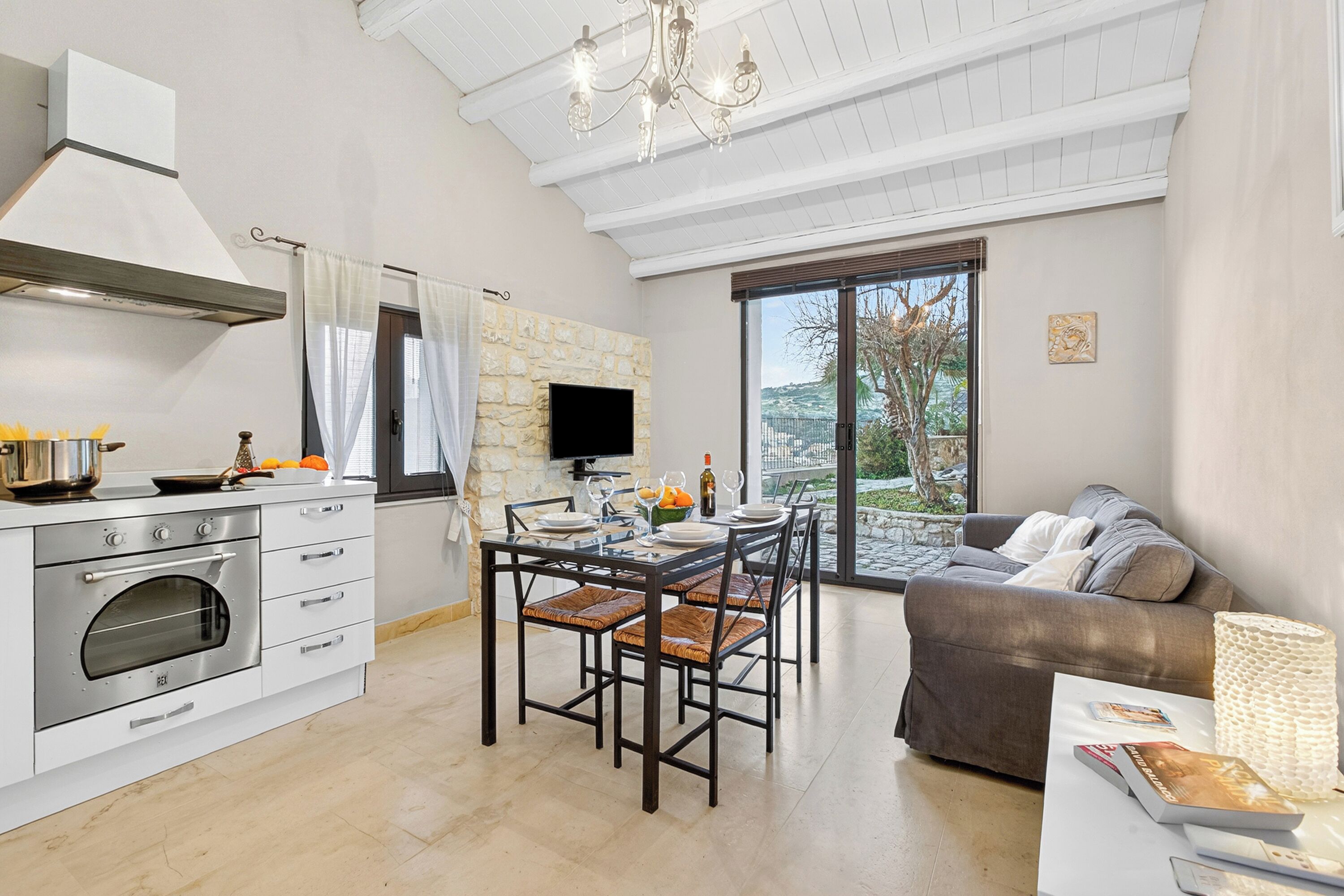 Eine moderne Küche mit Kamin aus Stein, Essbereich mit Stühlen, einer Couch und einem großen Fenster mit Blick.