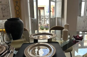 Een eettafel gedekt met borden, bestek en een vaas.