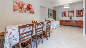 Un coin repas avec une table dressée pour quatre personnes, un canapé et un meuble contenant des objets décoratifs.