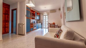 Un salon avec un canapé et un coin repas comprenant une table et des chaises.