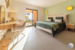 A bedroom with a bed, a desk, a chair, a nightstand, and a view of the outdoors. - Apartment of 85m² – 2 Suites – Swimming pool & tennis (Grosseto-Prugna)