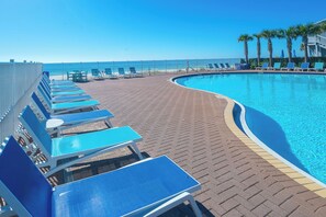 A poolside area with lounge chairs and a clear view of the ocean. - Beach Chair Service Included - Gulf front Master - Bunk Room - Near Pier Park (Panama City Beach)