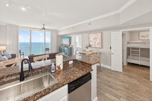 A modern kitchen with granite countertops, a dishwasher, and a large window overlooking the ocean. - Beach Chair Service Included - Gulf front Master - Bunk Room - Near Pier Park (Panama City Beach)
