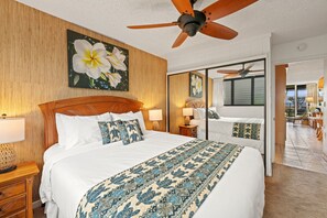 A hotel room with a large bed, wooden headboard, ceiling fan, and a view of the outdoor area. - SUMMER SALE! Ocean View Paradise,1BR condo in Lahaina - Polynesian Shores 106 (Lahaina)