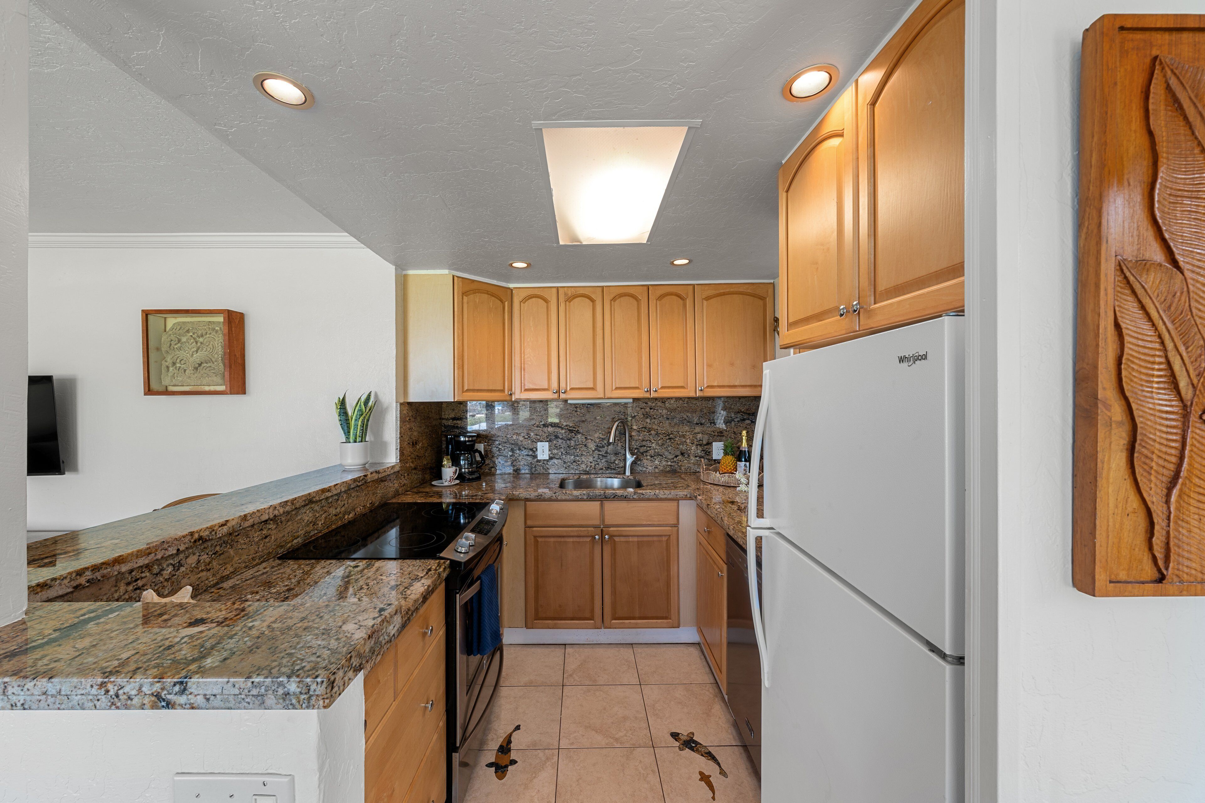 A kitchen with granite countertops, wooden cabinets, a built-in oven, and a refrigerator.