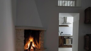 A fireplace with a fire, a kitchen area, and a small window. - Alma-Chalet di Lago (Capodimonte)