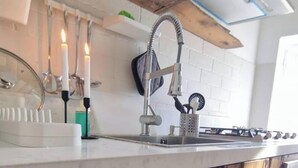 A kitchen with a stainless steel sink, a gas stove, and a wooden ceiling beam. - Alma-Chalet di Lago (Capodimonte)