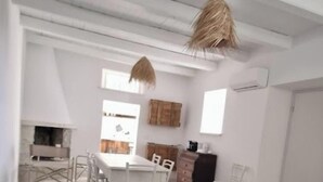A spacious room with a high ceiling, exposed beams, a dining area with a table and chairs, and a kitchen area with cabinets and a stove. - Alma-Chalet di Lago (Capodimonte)