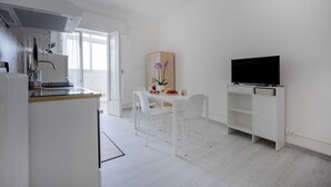 Et moderne køkken med hvide skabe, en indbygget komfur og et spiseområde med bord og stole.