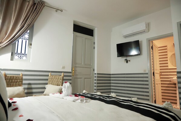 A hotel room with a bed, a television, a door, and a window with curtains. - Riad Allal (Marrakech)