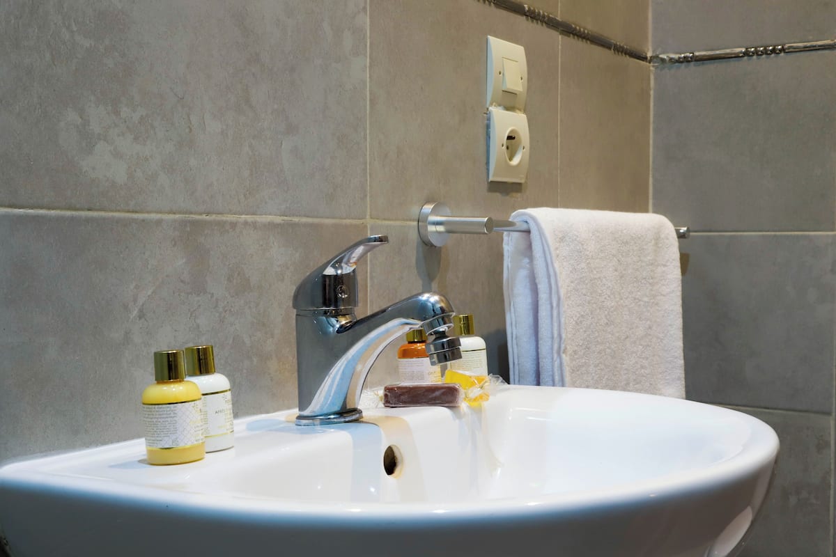 A bathroom sink with a faucet, two bottles of soap, and a towel hanging on a rack.