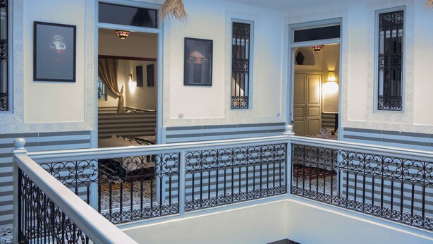 A multi-level interior with a balcony, ornate railings, and framed artwork on the walls. - Riad Allal (Marrakech)