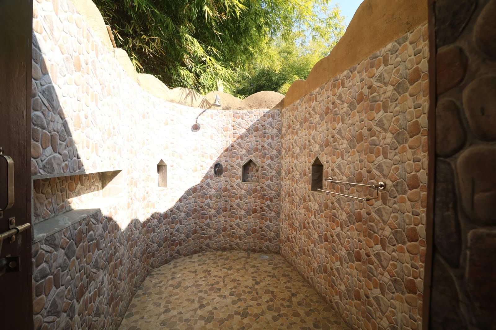 Un bagno con pareti in pietra, una piccola finestra e una porta.