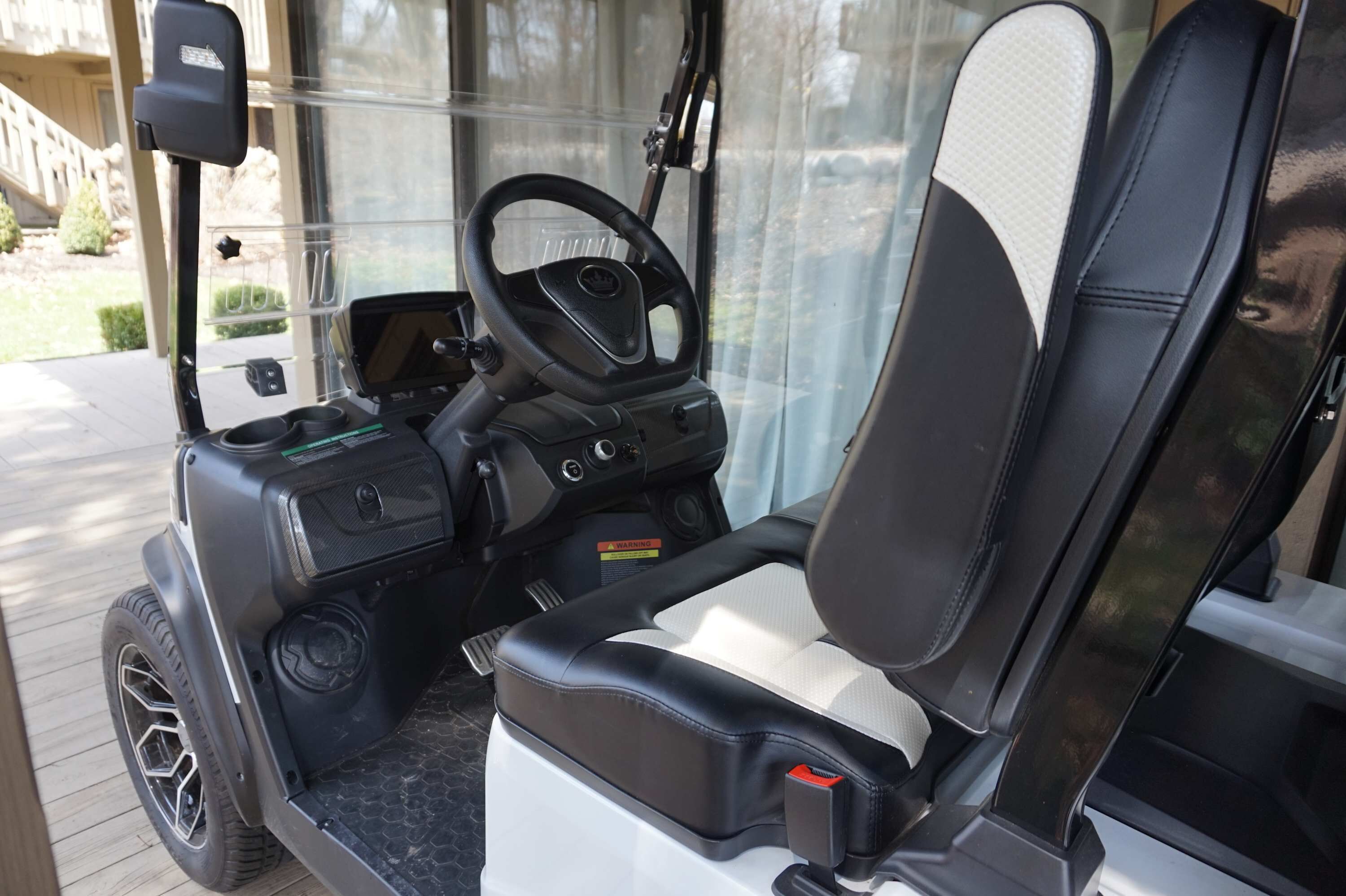 Interior de un carrito de golf con volante, asiento y panel de control.