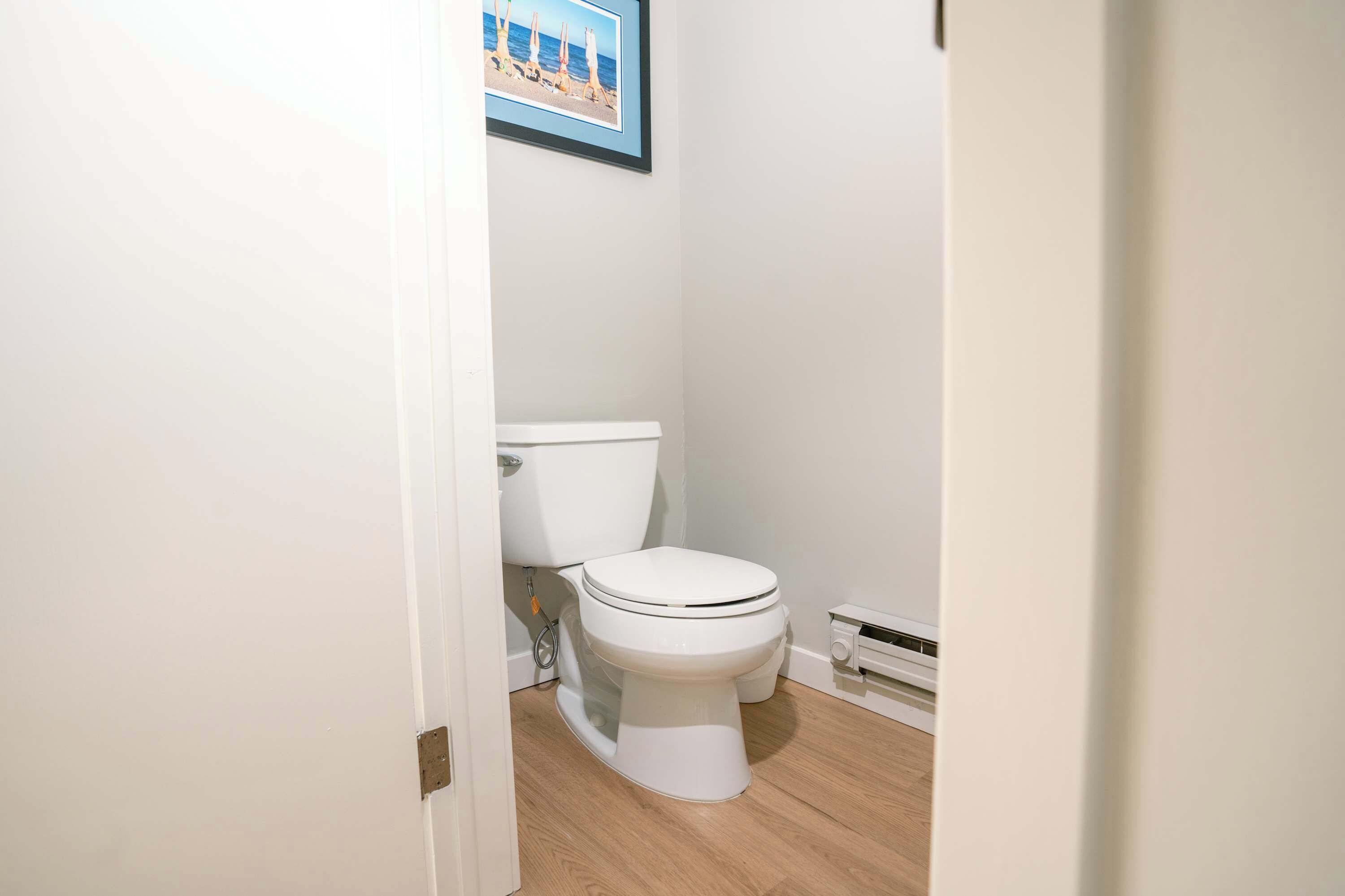 A bathroom with a toilet, a framed picture on the wall, and a radiator.