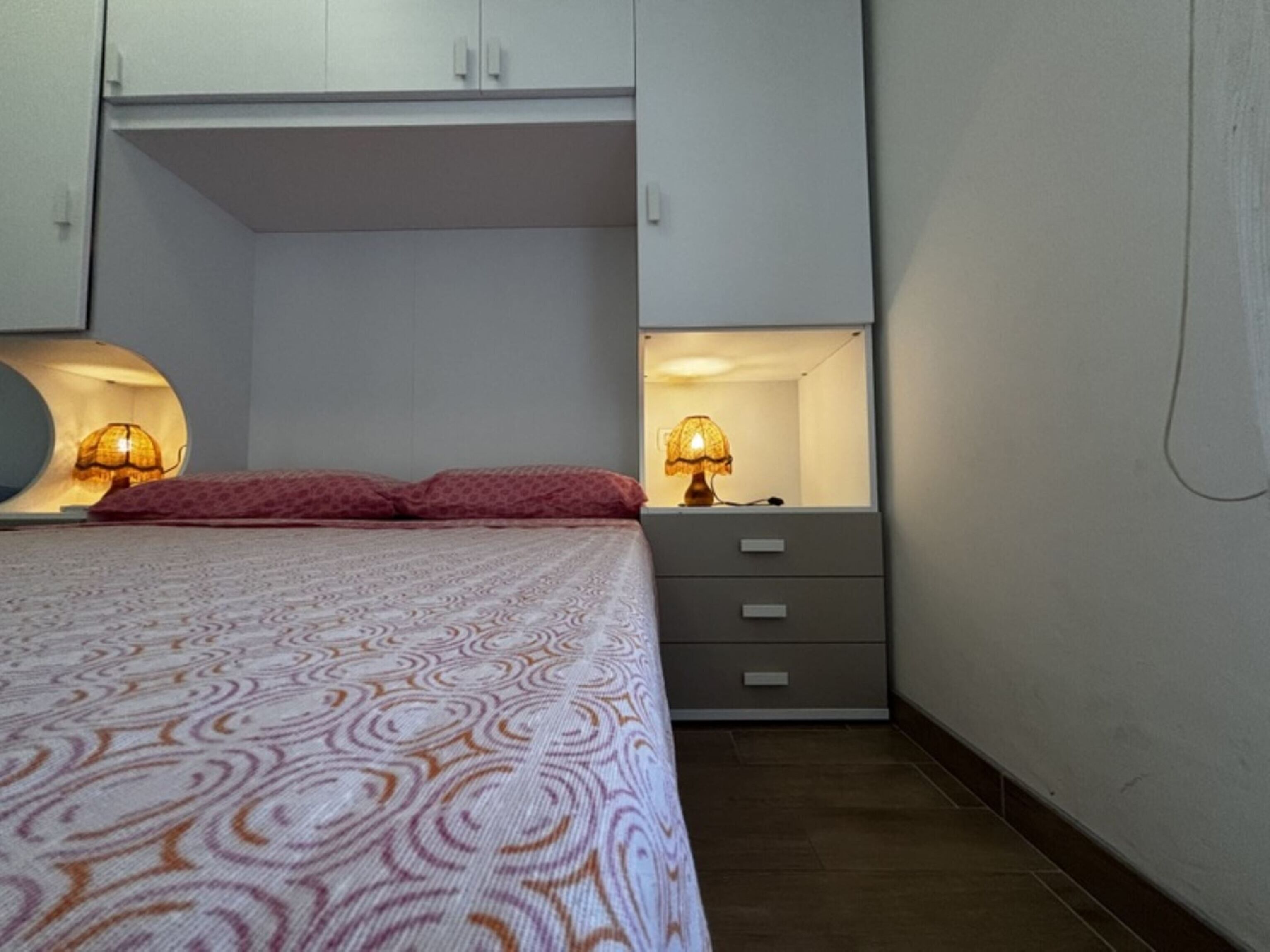 Une chambre à coucher comprenant un lit, deux lampes de chevet, une commode et une armoire.