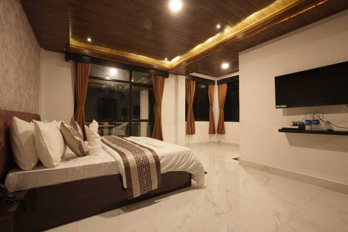 Une chambre à coucher moderne avec un grand lit, un téléviseur fixé au mur et un sol en marbre.