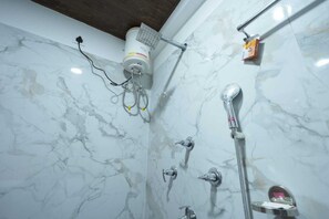 A bathroom with a marble wall, a showerhead, a handheld shower, and a towel rack. - Longitude Homestay (Kalimpong)