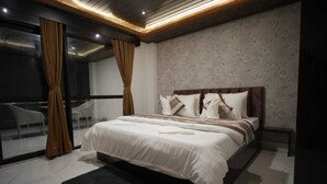 A modern bedroom with a large bed, a glass door leading to a balcony, and a patterned wallpaper. - Longitude Homestay (Kalimpong)