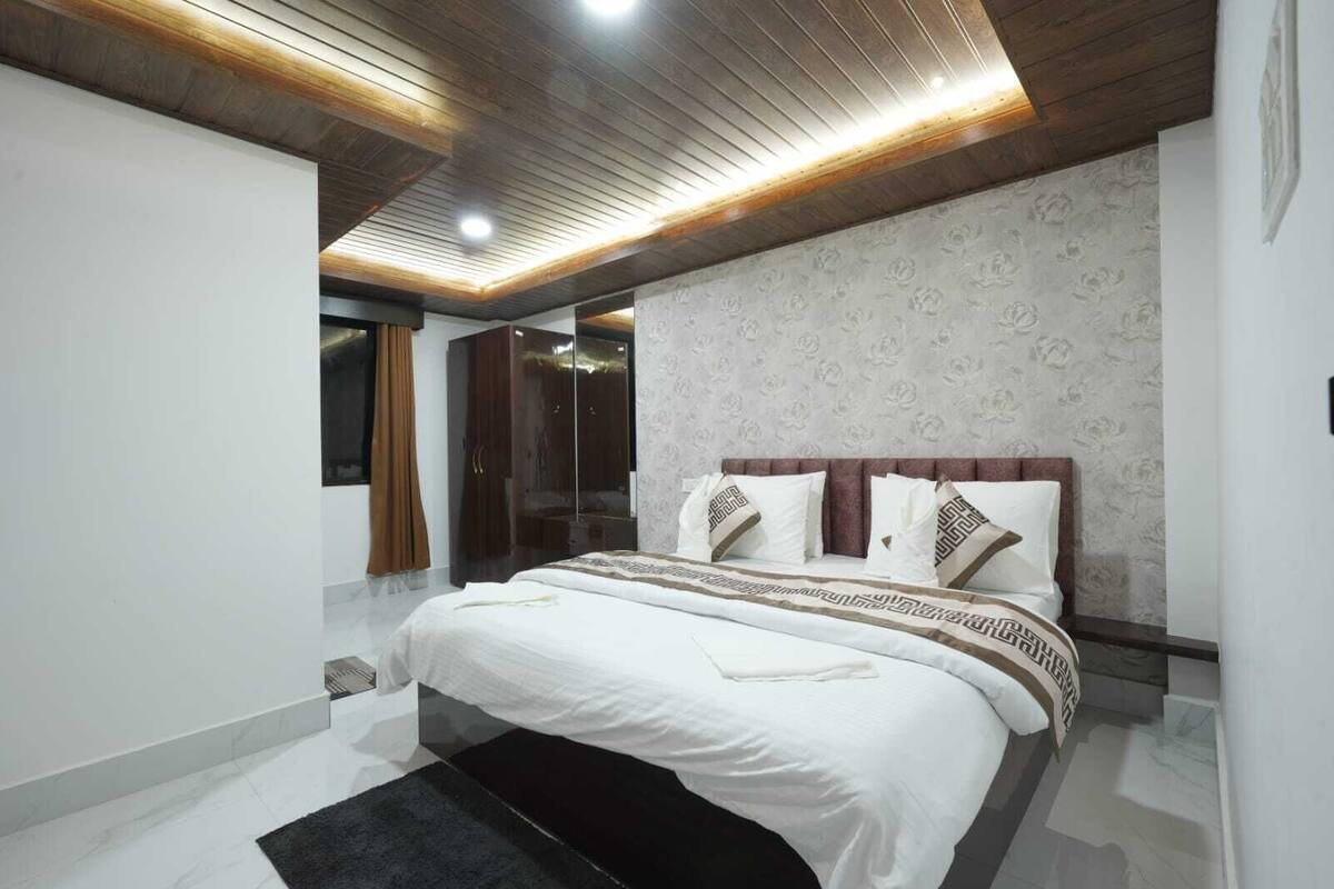 Une chambre à coucher moderne avec un grand lit, une armoire et un miroir.