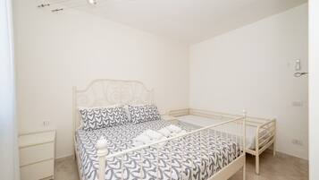 Une chambre avec un lit simple, une couvre-lit à motifs, une table de chevet et une petite table de nuit.