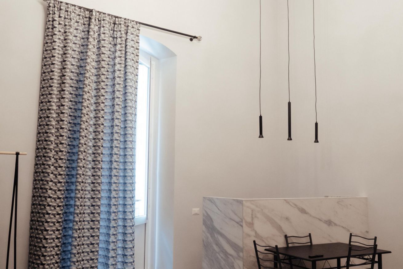 A room with a dining table, chairs, a curtain, and pendant lights.