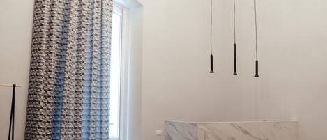 A room with a dining table, chairs, a curtain, and pendant lights.
