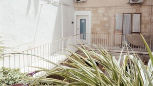 A white building with air conditioning units, a door, and a balcony with a railing. - GuestHost - Guest Host - Elegant Studio Apt Maison Vittoria (Bari)