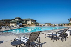 A swimming pool with lounge chairs and a building with a balcony.