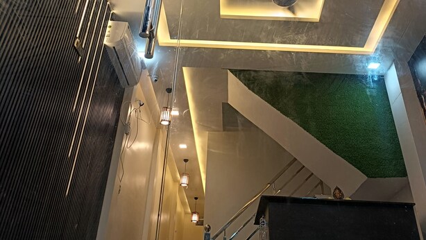 A modern interior with a central ceiling light fixture, a staircase, and a wall-mounted air conditioning unit. - Gita Raman Palace (Ayodhya)
