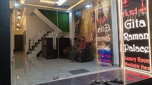 A hotel entrance with a glass facade, a staircase, and a sign advertising luxury rooms. - Gita Raman Palace (Ayodhya)